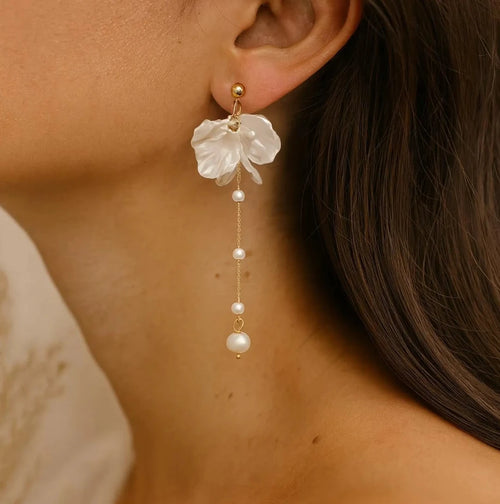 Close-up of a woman wearing floral earrings with pearl drops.